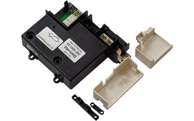Schwarzes rechteckiges Elektronikgehäuse mit mehreren Steckverbindern, einem weißen Etikett, zwei losen weißen Kunststoffabdeckungen und zwei kleinen schwarzen Halteclips auf weißem Hintergrund