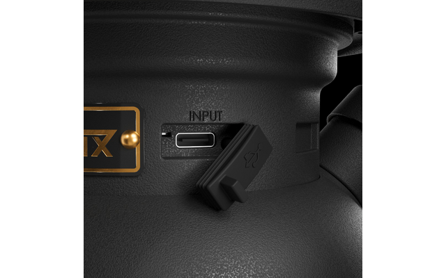 Primo piano di un involucro nero testurizzato con una porta USB-C etichettata "INPUT", un tappo di gomma parzialmente aperto e una piastra dorata con la scritta "TX"