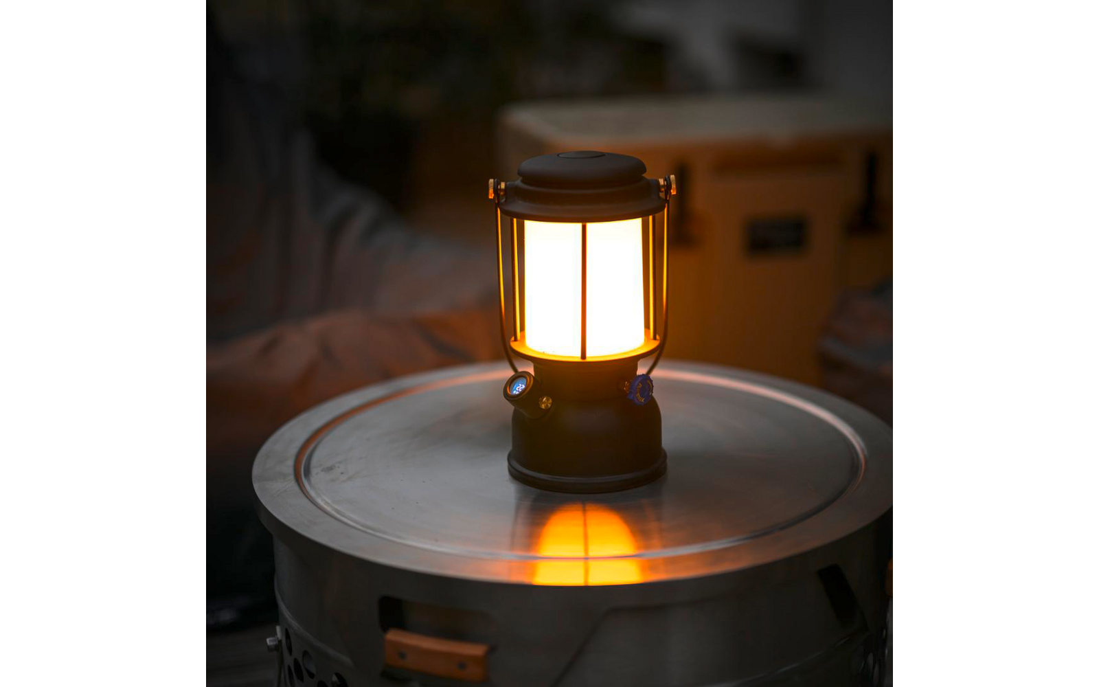 Una lanterna accesa su una superficie metallica rotonda, la sua luce si riflette sulla superficie, oggetti sfocati sullo sfondo