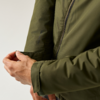 Hände, die den Klettverschluss am Ärmel einer olivgrünen Jacke anpassen; sichtbarer Reißverschluss und Teil des Oberkörpers