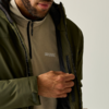 Teil des Oberkörpers einer Person mit Bart, die eine olivgrüne Jacke öffnet; darunter ein hellbraunes Fleece mit Reißverschluss und sichtbarem 'Regatta'-Logo
