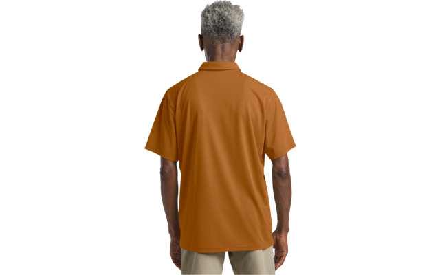 Rückansicht einer stehenden Person mit kurzem grauem Haar, orangefarbenem Kurzarm-Poloshirt und hellen Hosen