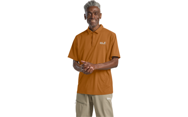 Person steht lächelnd, kurze graue Haare, trägt orangefarbenes Poloshirt mit kleinem Logo auf der Brust, khakifarbene Hose, gefaltete Hände, freigestellt auf weißem Hintergrund