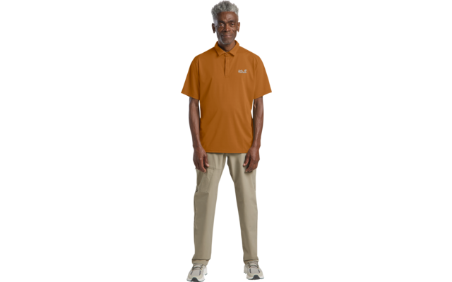 Person steht frontal, trägt orange Poloshirt mit Logo, beige Hose, weiße Sneaker, kurzes graues Haar