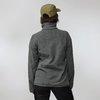 Person von hinten, trägt olivgrüne Baseballkappe, graue Fleecejacke mit hohem Kragen und schwarze Hose vor hellem Hintergrund
