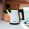 White electric kettle on a white countertop, with a woven basket and plant in the background