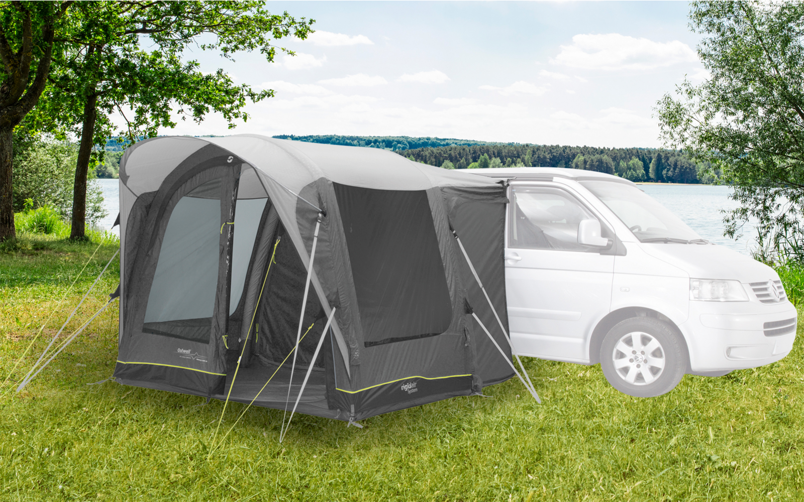 Wohnmobil mit angebautem grauen Vorzelt auf einer Wiese bei bewölktem Himmel