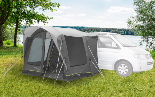Wohnmobil mit angebautem grauen Vorzelt auf einer Wiese bei bewölktem Himmel