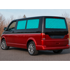 Red van, blue quilted window covers, parked on a road; leafless trees and sky in the background