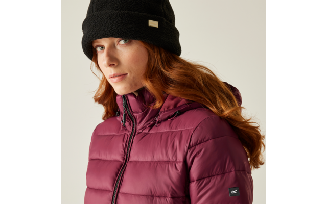 Femme aux cheveux roux portant un bonnet noir et une veste matelassée bordeaux