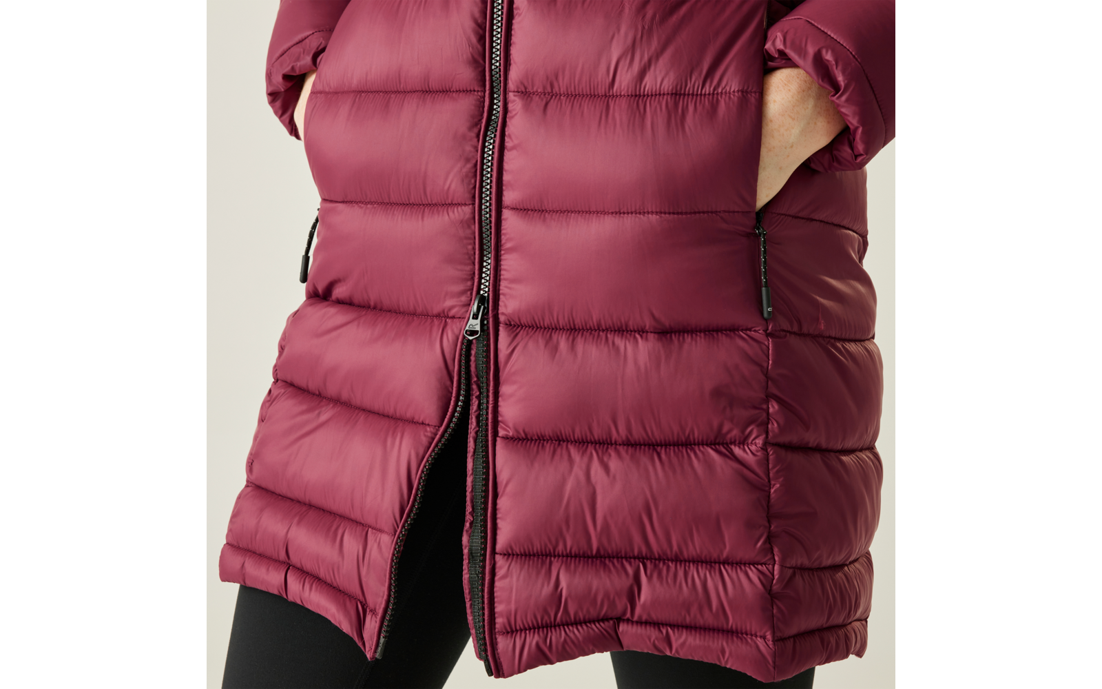 Rosa oder dunkelrote gesteppte Jacke mit Reißverschluss und zwei Taschen, Hände in den Taschen