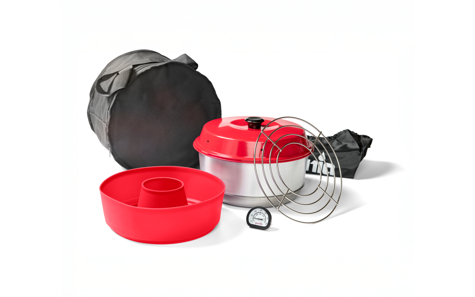 Rote Silikonform mit zentralem Rohr, rundes Metallgefäß mit rotem Deckel, mehrere runde Drahtgitter, kleines rundes Thermometer mit Zifferblatt, runde schwarze Tragetasche und schwarzer Stoffbeutel auf weißem Hintergrund