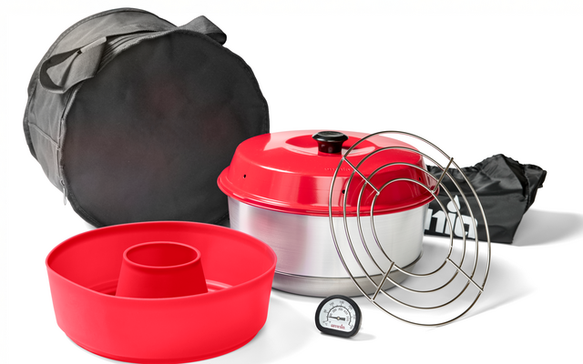 Rote Silikonform mit zentralem Rohr, rundes Metallgefäß mit rotem Deckel, mehrere runde Drahtgitter, kleines rundes Thermometer mit Zifferblatt, runde schwarze Tragetasche und schwarzer Stoffbeutel auf weißem Hintergrund