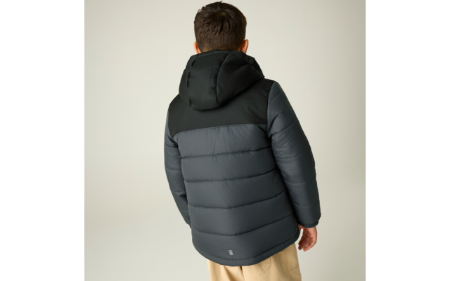 Person von hinten, trägt dunkle gesteppte Kapuzenjacke und hellbeige Hose, neutraler heller Hintergrund