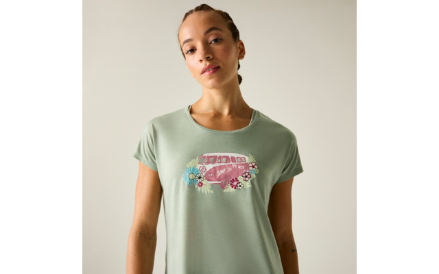 Frau vor hellem Hintergrund, trägt hellgrünes T-Shirt mit rosa Campervan-Illustration und Blumen