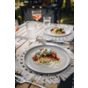 Une table à manger en plein air dressée avec une assiette de nourriture, un verre d'eau et des couverts