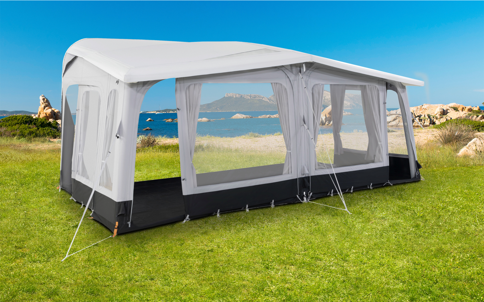 Tente de jardin blanche avec grandes fenêtres sur herbe verte avec vue sur la mer en arrière-plan