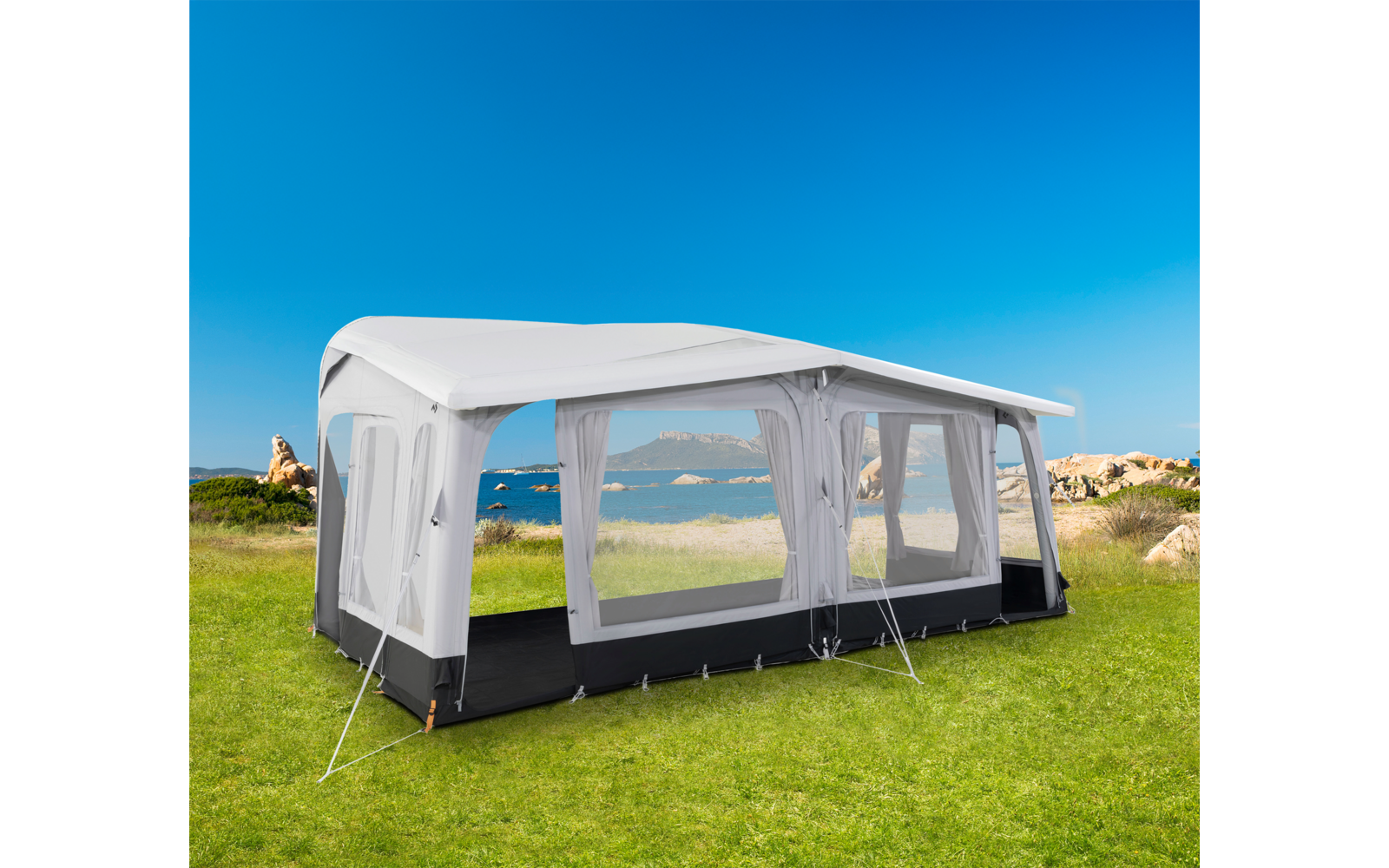 Weißes Gartenzelt mit großen Fenstern auf grünem Rasen mit Blick auf das Meer im Hintergrund