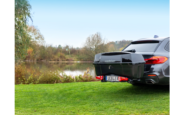 Vue arrière d'une voiture noire au bord d'un lac avec des arbres en arrière-plan