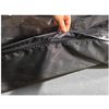 Main tenant une poche zippée ouverte en tissu noir texturé ; surface grise visible en dessous