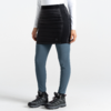 Partie inférieure du corps d'une femme portant un pantalon jupe noir, des leggings bleus et des chaussures noires sur fond blanc