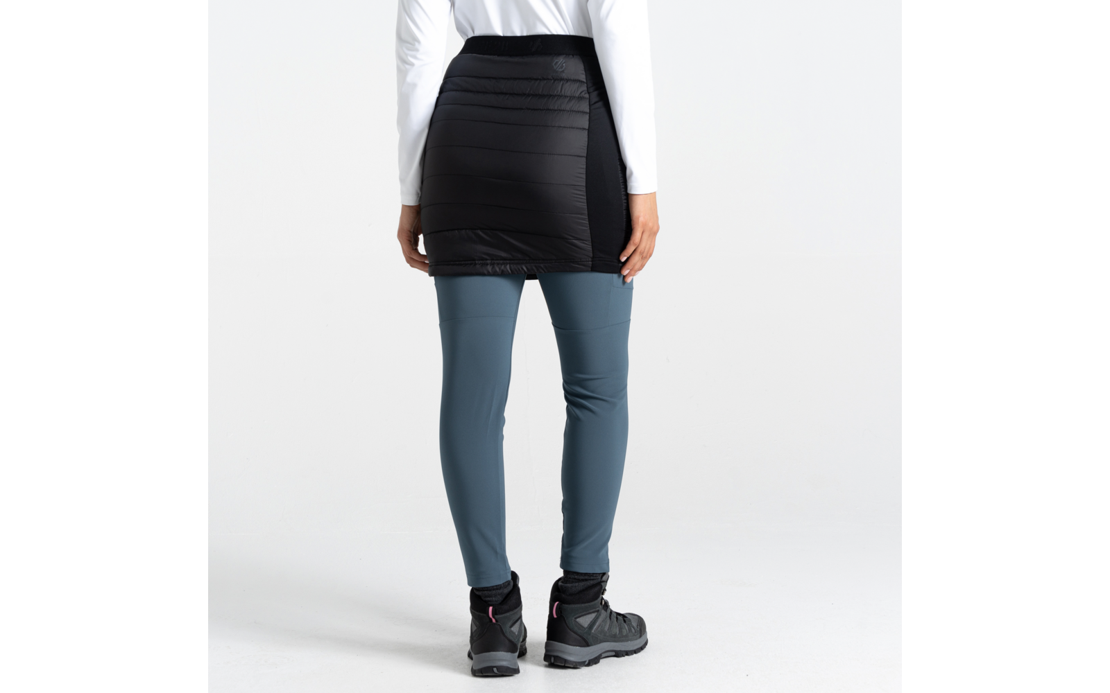 Personne vue de dos portant une jupe noire par-dessus un legging bleu et des bottes noires