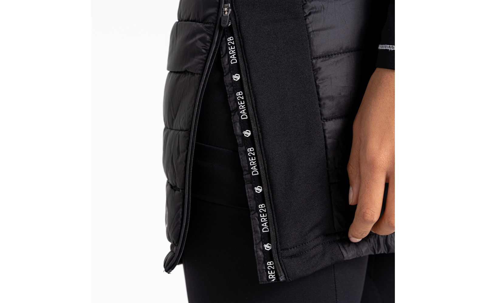 Gros plan d'une main à côté d'un manteau matelassé noir avec une fermeture éclair visible