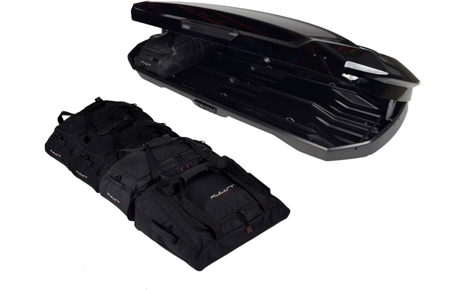 Coffre de toit noir ouvert avec intérieur visible à côté de trois sacs de voyage noirs sur fond blanc