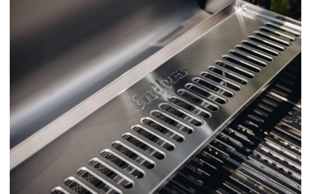 Nahaufnahme eines Edelstahlgehäuses mit gelochter Metallplatte, eingraviertem Schriftzug "Enders" und sichtbaren Grillrosten