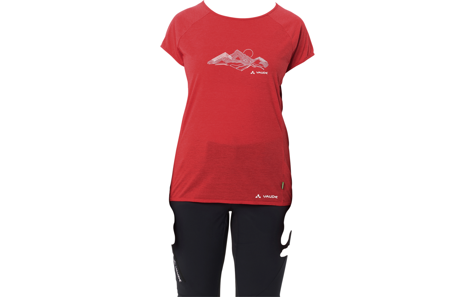 Persona in piedi di fronte alla fotocamera su sfondo bianco, indossa una maglietta rossa a maniche corte con disegno di montagna e pantaloni neri, capelli biondi raccolti, braccia rilassate ai lati