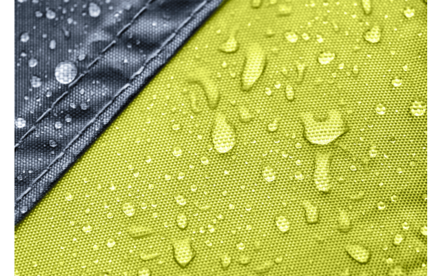 Green textured fabric with scattered water droplets and a diagonal gray fabric strip in the top left