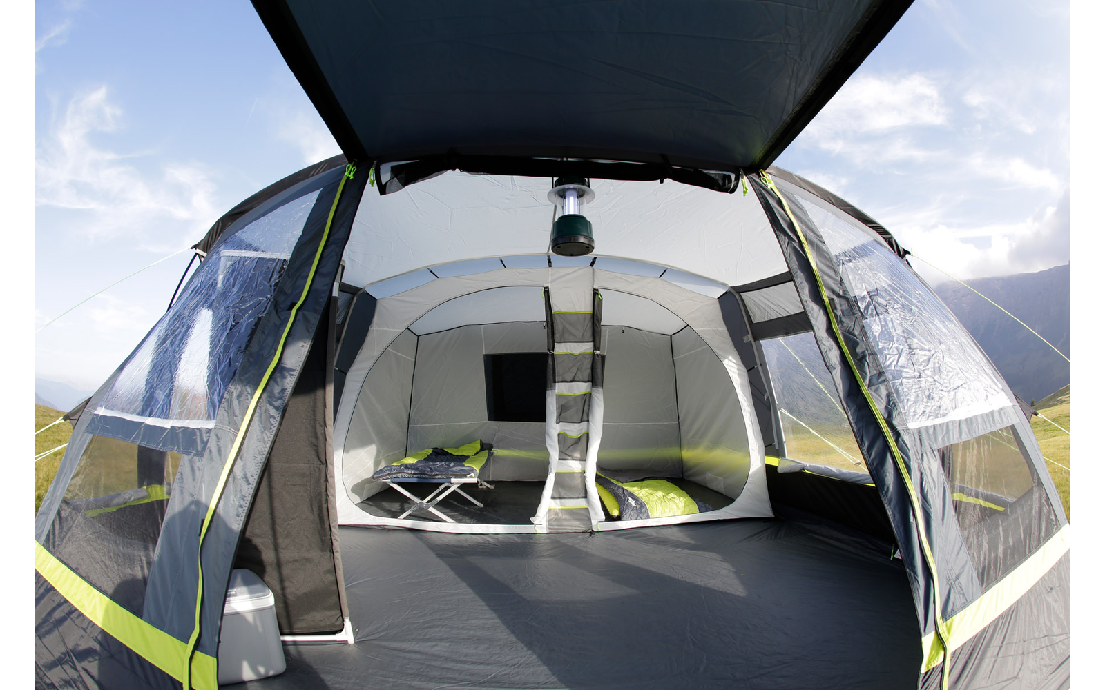 Innenansicht eines aufgestellten Zeltes mit geöffnetem Eingang und Blick auf eine Wiese im Hintergrund