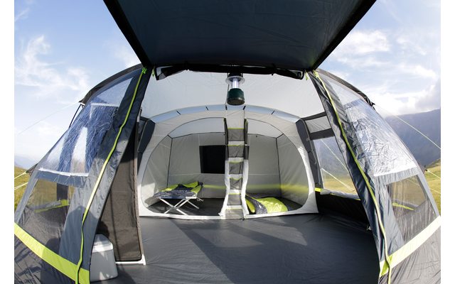 Innenansicht eines aufgestellten Zeltes mit geöffnetem Eingang und Blick auf eine Wiese im Hintergrund