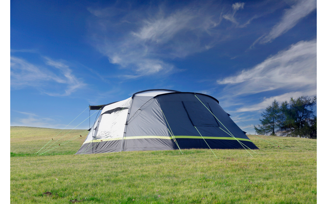 Zelt steht auf einer grünen Wiese unter blauem Himmel mit Wolken