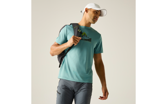 Person in türkisem T-Shirt mit Berggrafik, grauer Hose, weißer Kappe und Rucksack über der rechten Schulter vor hellem Hintergrund