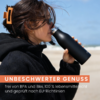 Person trinkt aus einer schwarzen Flasche am Strand, trägt schwarze Jacke, Sonnenbrille, Haarspange und goldenen Creolen; Hintergrund Sand, Meer und blauer Himmel; orangener Banner mit weißem Text 'UNBESCHWERTER GENUSS' und kleinem Text 'frei von BPA