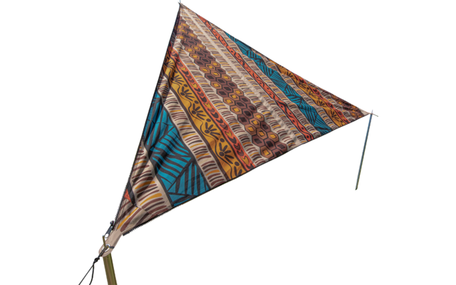 Colorfully patterned triangular tarp on a meadow with blue sky and trees