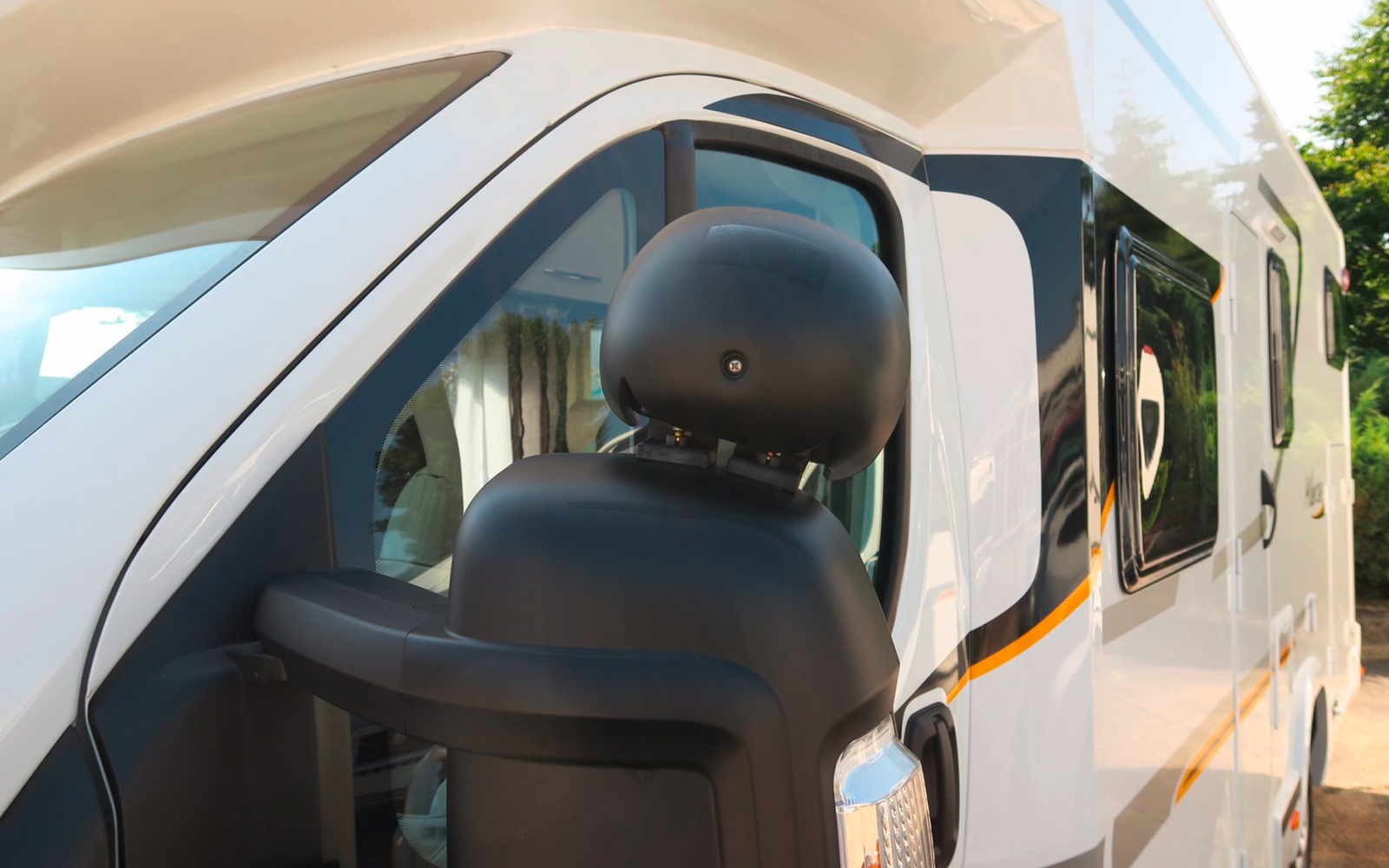 Vista exterior de una autocaravana blanca con espejo lateral negro y ventana