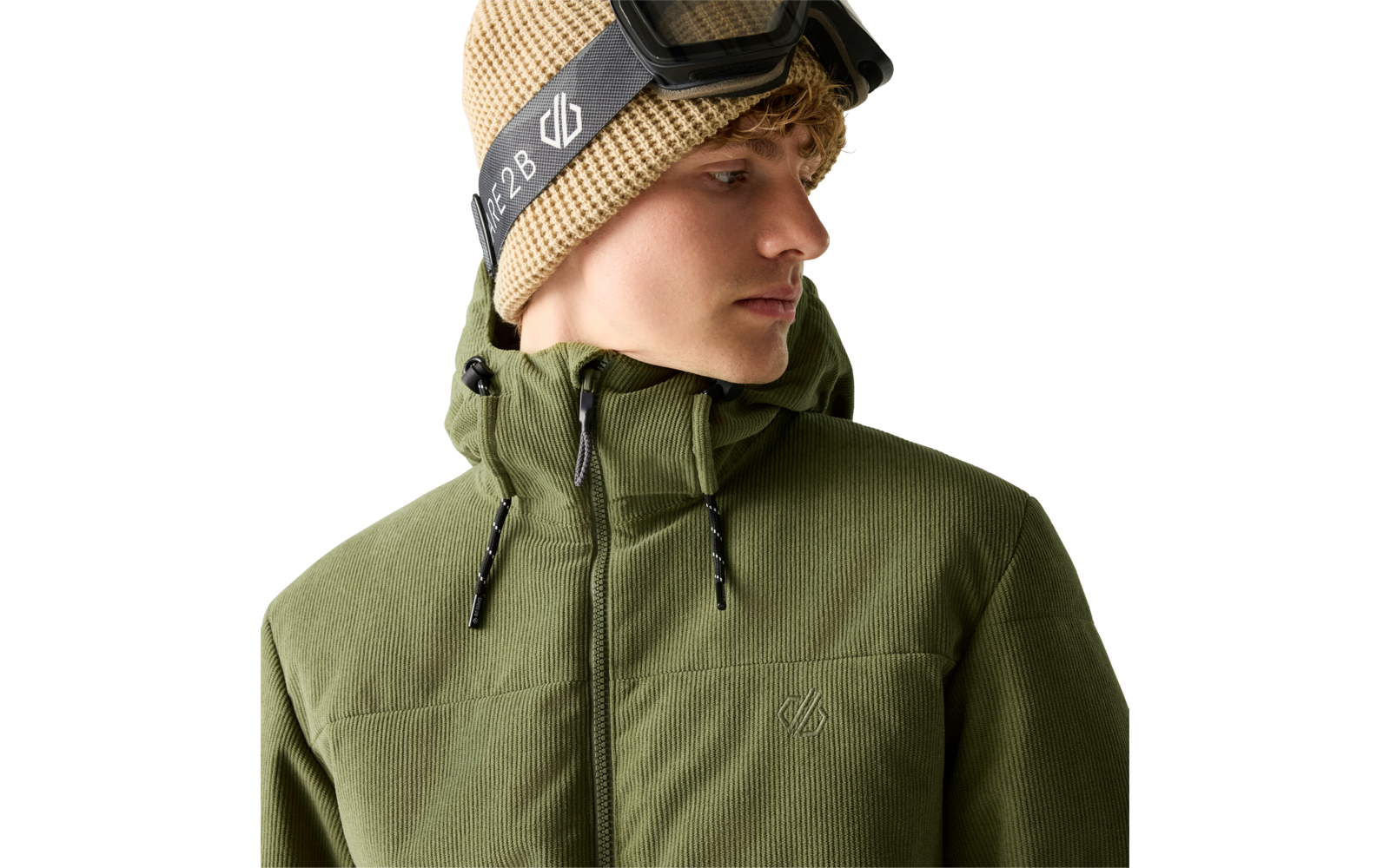 Person mit lockigem blondem Haar, beige Strickmütze und Skibrille auf dem Kopf, trägt olivegrüne Kapuzenjacke, Blick nach rechts