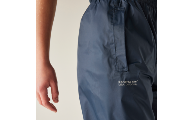 Close-up van de heup en arm van een persoon, donkerblauwe broek met zijzak en wit "Regatta Great Outdoors"-logo