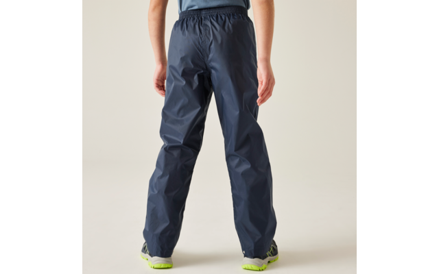 Achteraanzicht van taille tot voeten: persoon draagt donkerblauwe regenbroek en grijze schoenen met neon groene zolen