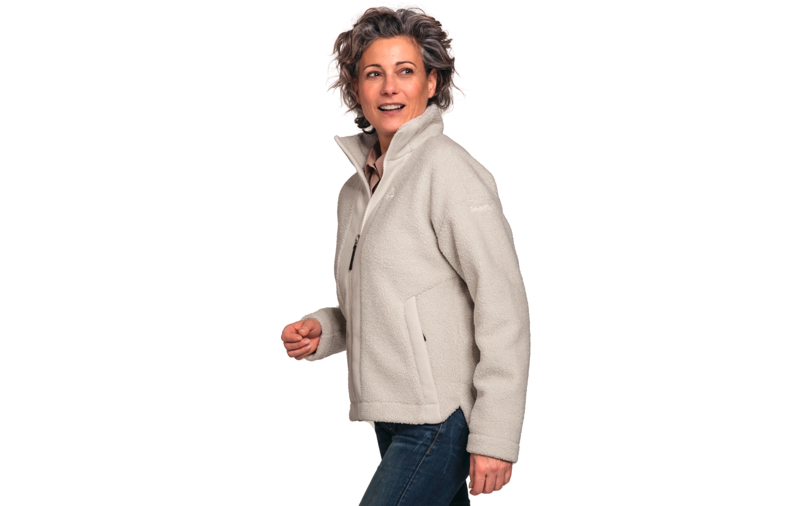 Person mit kurzen, lockigen graubraunen Haaren, helle Fleecejacke mit Reißverschluss und blaue Jeans, schaut nach rechts, weißer Hintergrund