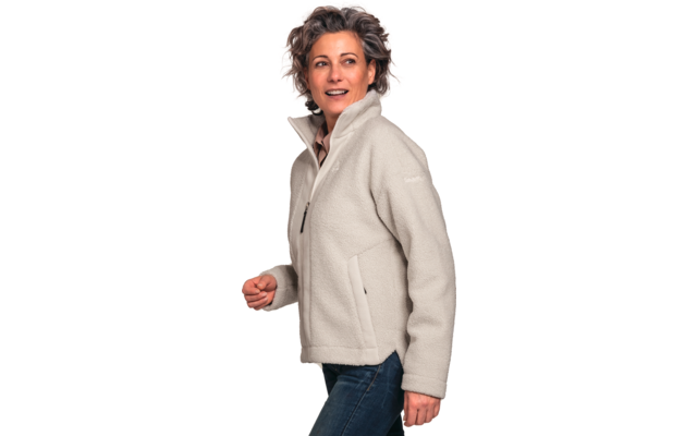 Person mit kurzen, lockigen graubraunen Haaren, helle Fleecejacke mit Reißverschluss und blaue Jeans, schaut nach rechts, weißer Hintergrund