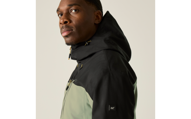 Person in Dreiviertelansicht trägt eine zweifarbige Kapuzenjacke (schwarze Kapuze, hellgrüner Oberkörper), Blick nach links, heller einfarbiger Hintergrund