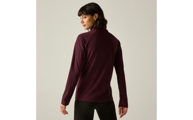 Personne vue de dos, portant un pull à col roulé bordeaux et un pantalon noir sur fond uni clair