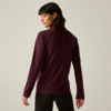 Personne vue de dos, portant un pull à col roulé bordeaux et un pantalon noir sur fond uni clair