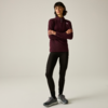 Femme en pied aux cheveux foncés et frange, debout les bras croisés, portant un haut bordeaux à manches longues avec fermeture éclair courte, leggings noirs et baskets grises sur fond clair