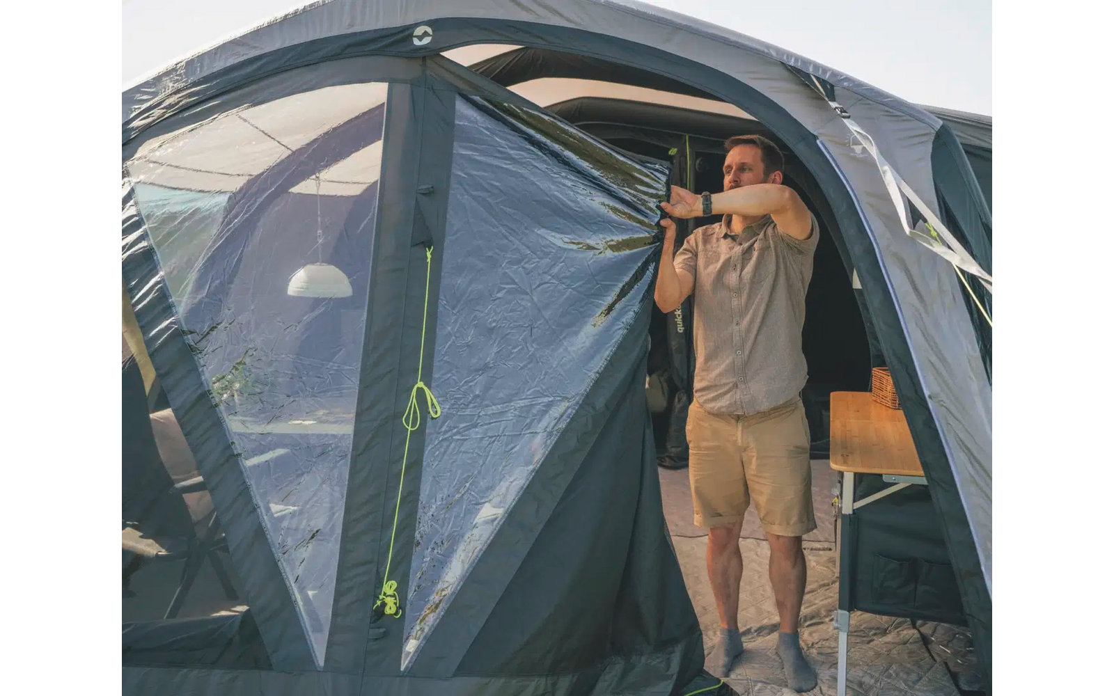 Mann mit Fernglas vor einem Zelt an einem Auto stehend