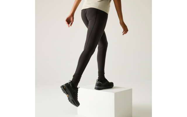 Unterkörper einer Person in schwarzen Leggings und schwarzen Sportschuhen, ein Fuß auf einem weißen Würfel