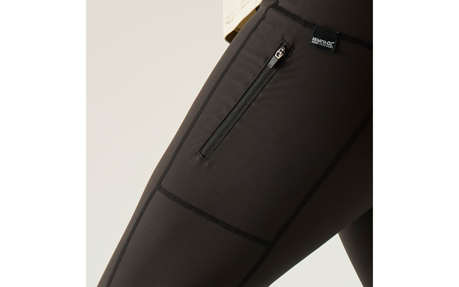 Nahaufnahme von schwarzen Leggings mit seitlicher Reißverschlusstasche und kleinem Markenlabel